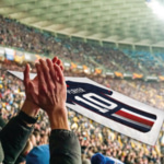Tifo imprimé tenu par des supporters dans une tribune de stade